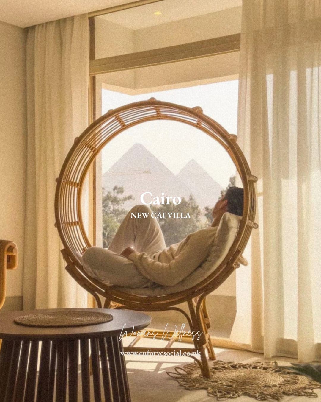 A round rattan chair by the window at New Cai Villa, the pyramids of Giza framed behind it